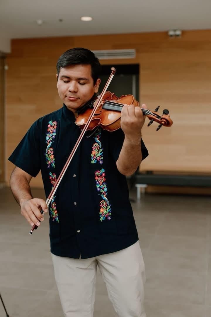 Man in black embroidered shirt playing violin indoors